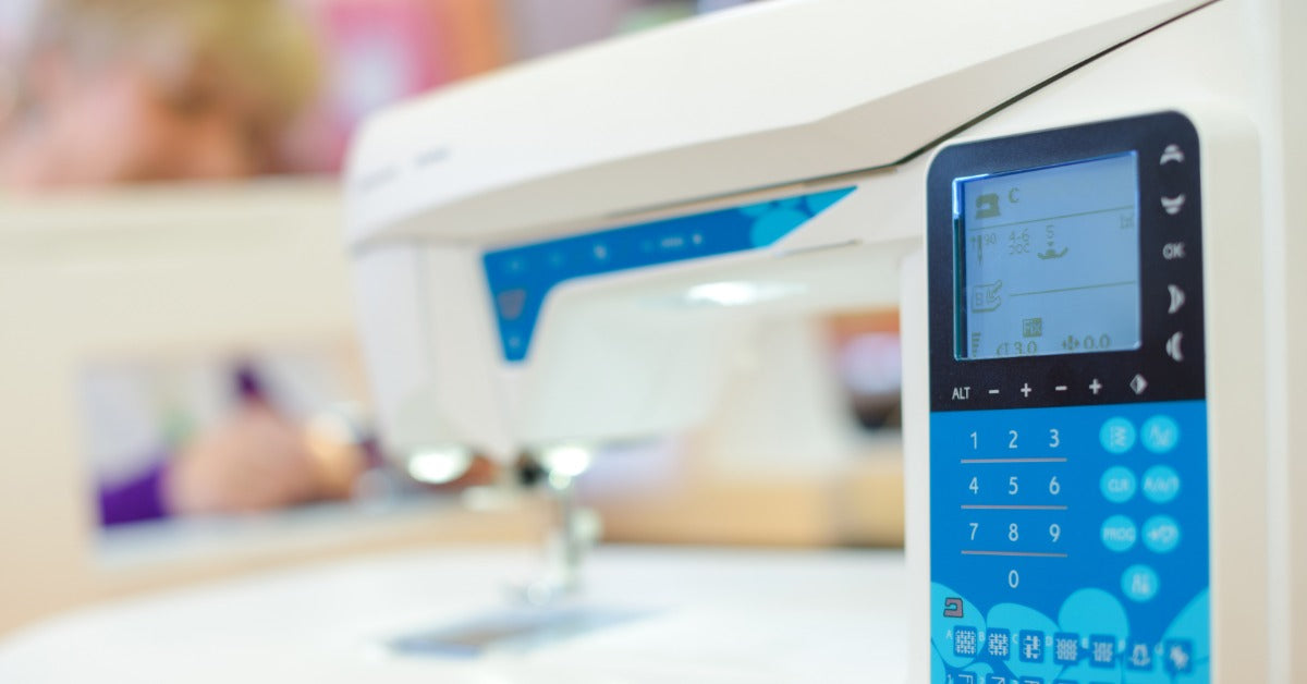 A computerized sewing machine has a digital display with stitch settings and numbered buttons on the front.