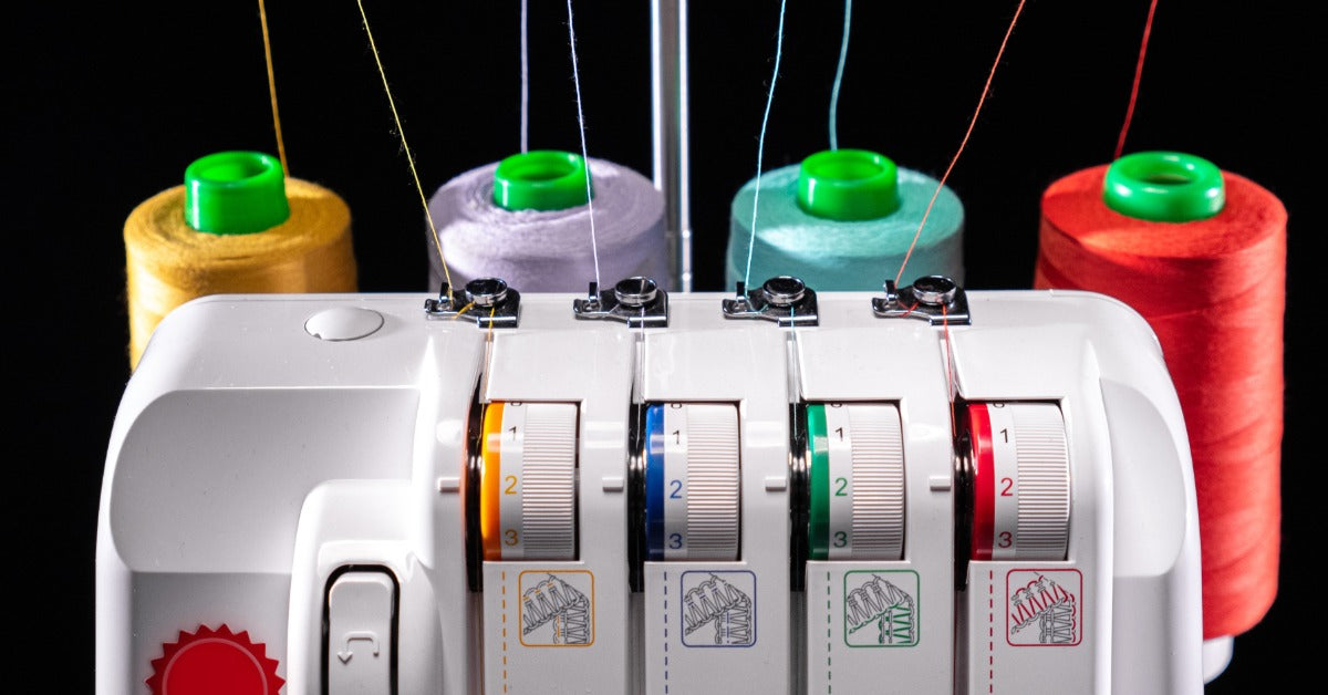 Yellow, lavender, turquoise, and red threads feed from cones behind a serger through the machine's top guides.