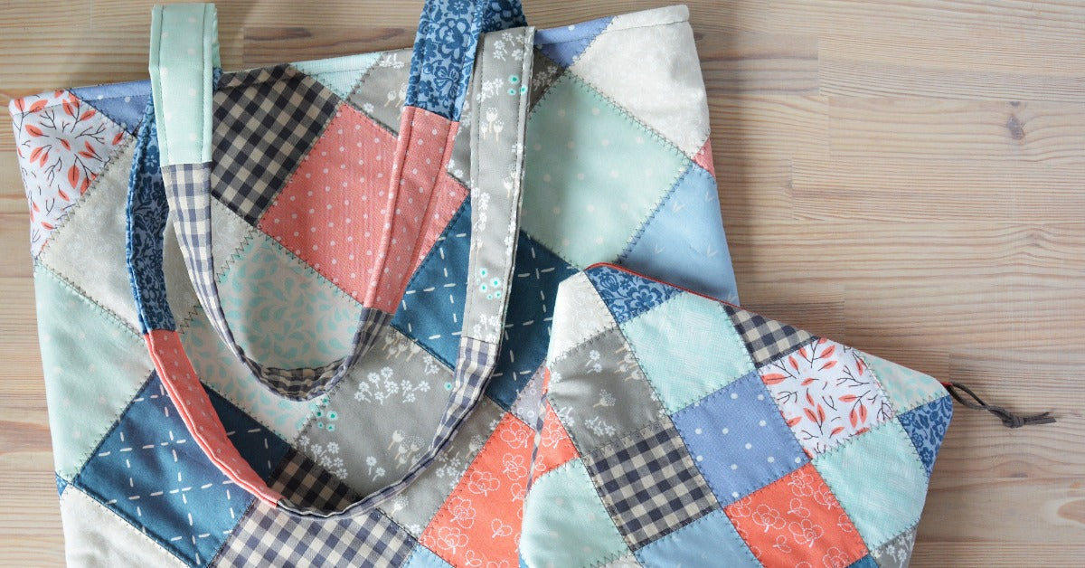 A patchwork quilted tote bag and matching zippered pouch feature blue, coral, mint, gray, and checkered fabric squares.